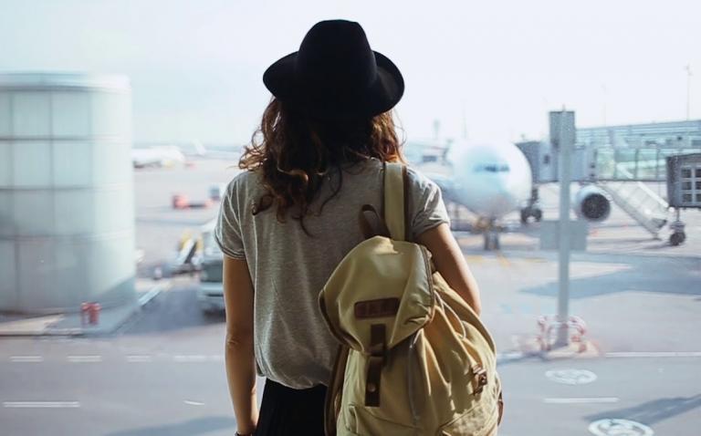 woman standing in front of an airport windows with planes